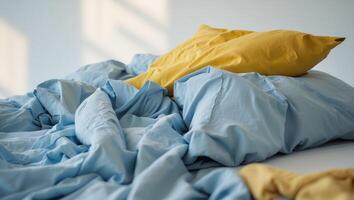 A messy bed with a yellow pillow and blue sheets photo
