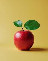 Fresh Red Apple with Green Leaf on Bright Yellow Background photo