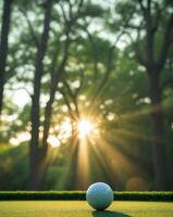 a golf ball on a vibrant green putting green with sunlight streaming through trees in the background photo
