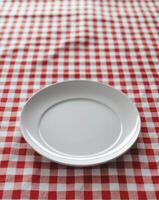 Empty plate on red and white checkered tablecloth photo