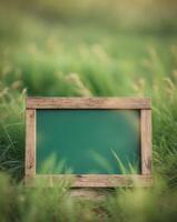 A wooden frame with a green chalkboard in the grass photo