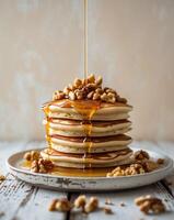 A stack of pancakes with walnuts and syrup photo