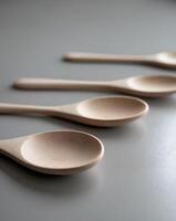 three wooden spoons are lined up on a gray surface photo