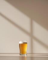 A glass of beer on a table in front of a wall photo