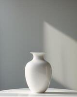 A white vase sitting on a table in front of a wall photo