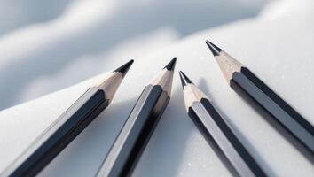 three black pencils are lined up on a white surface photo
