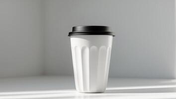 A white coffee cup with a black lid on a table photo