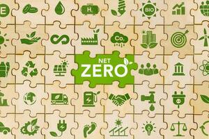 The concept of net zero and carbon neutrality Green net zero icon on wooden jigsaw puzzle For the goal of net zero greenhouse gas emissions Long term climate neutral strategy on green background photo