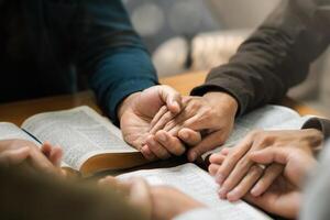 Group of young Christians praying, holding hands and praying together The concept of praying to God in the home as a team Pray to God with the Bible for forgiveness and faith. photo