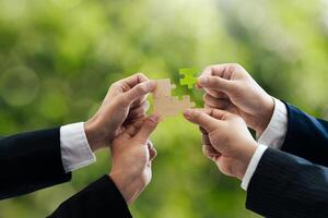 Office workers holding a jigsaw puzzle, teamwork and unity. Charity, volunteering, problem solving, business unity, business teamwork, success and strategy. Green background. photo