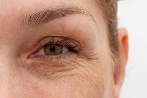 Close up cropped eye with wrinkles of middle aged caucasian woman looking at camera photo