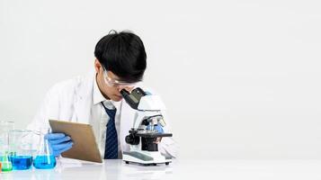 Portrait Asian man student scientist Wearing a doctor gown in the lab looking hand at chemist. caused by mixing reagents in scientific research laboratories with test tubes and microscope on the table photo