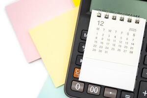 Simple desk calendar for DECEMBER 2025 on calculator. Calendar concept with copy space. 2025 DEC calendar. photo