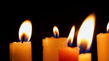 Close up of multiple burning candles with a dark background. video