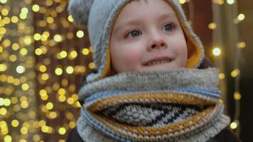 Small child jumps, trying to warm up in bitter cold outside in winter, standing against background of golden lights of garland video