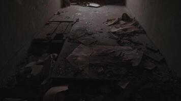A dimly lit, abandoned hallway that is covered in debris and remnants from a once vibrant past activity video