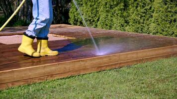 Person Pressure Washing Wooden Deck in Garden with Evergreen Trees video