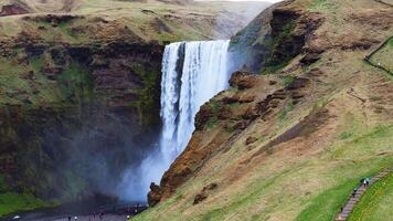 Majestic Skogafoss Waterfall with Visitors in Iceland's Rugged Landscape video