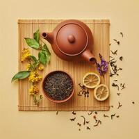Herbal tea preparation with dried leaves, lemon slices, and fresh herbs on a bamboo mat photo