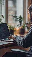 Focused individual working on laptop in cozy indoor space with plants and warm lighting photo