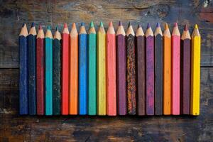 Colorful pencils arranged in a straight line on a wooden surface for creative activities photo
