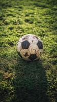 Worn soccer ball resting on grass field after a lively game in the afternoon light photo