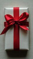 Gift wrapped in brown paper with a red ribbon on a dark surface photo