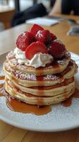 Stack of fluffy pancakes topped with whipped cream and fresh strawberries in a cozy cafe photo