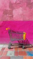 Shopping cart in front of vibrant pink wall on sunny day at urban location photo