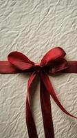 Gift wrapped in brown paper with a red ribbon on a dark surface photo