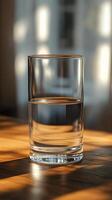 Glass of water reflecting sunlight on a wooden table near a window photo