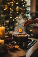 Festive holiday beverage preparation with spices and citrus near a decorated Christmas tree photo