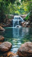 Majestic waterfall cascading into clear blue pool surrounded by rocky terrain in a serene landscape photo