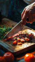 Hand slicing freshly cooked meat on a wooden cutting board with herbs and tomatoes nearby photo