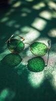 Stylish gold rimmed glasses resting on a green surface illuminated by soft light photo