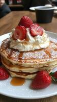 Stack of fluffy pancakes topped with whipped cream and fresh strawberries in a cozy cafe photo