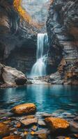 Majestic waterfall cascading into clear blue pool surrounded by rocky terrain in a serene landscape photo