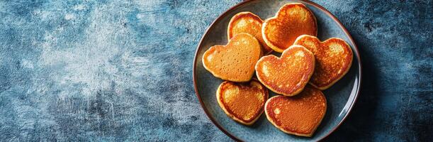 Delicious heart-shaped pancakes served on a blue plate with a textured background photo