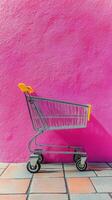 Shopping cart in front of vibrant pink wall on sunny day at urban location photo