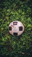Worn soccer ball resting on grass field after a lively game in the afternoon light photo