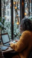 Focused individual working on laptop in cozy indoor space with plants and warm lighting photo