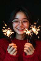 Celebratory young woman holding sparklers in cozy red sweater against dark background photo