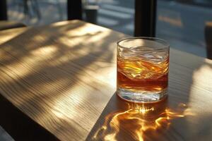 Whiskey glass on wooden table reflecting sunlight in a cozy indoor setting photo