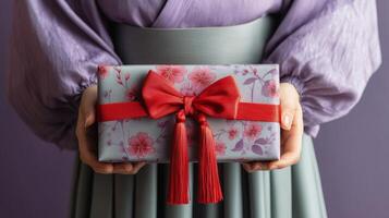 Beautifully wrapped gift held by individual in traditional attire in a cultural setting photo
