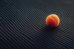 Bright orange tennis ball resting on a textured dark surface in a dramatic setting photo