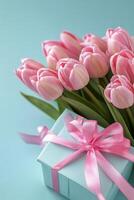 Beautiful bouquet of pink tulips arranged with a gift box on a light blue background photo