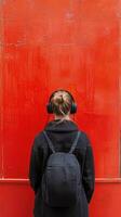 Young woman listening to music against a vibrant red wall during the day photo