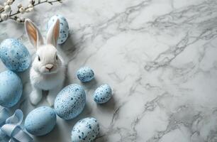 Sweet rabbit with blue eggs and spring flowers on marble surface during Easter celebration photo