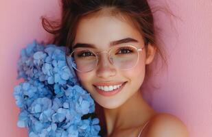 Smiling young woman with blue flowers against a pink background in a bright and cheerful setting photo