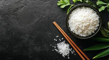 Delicious white rice served in a bowl with chopsticks and fresh herbs on a dark background photo